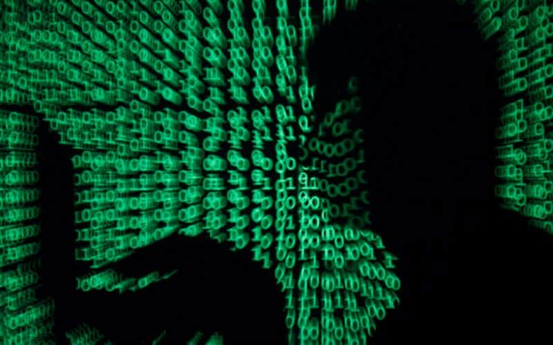 A visual representation of how cyber attacks happen, showing a silhouette against a background of green binary code.
