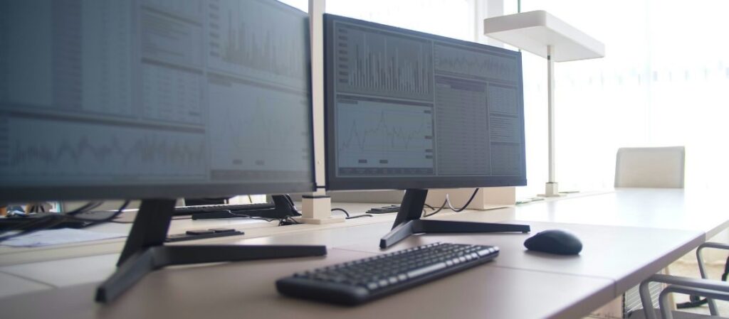 Modern desktop setup showing multiple monitors displaying graphs and dashboards for Remote IT Support operations.